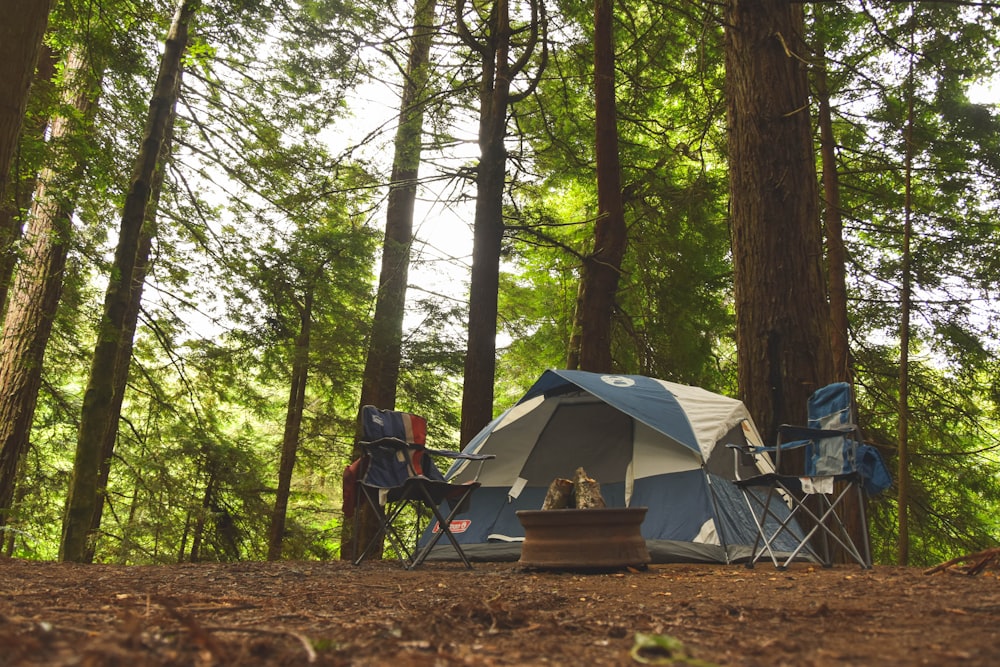 Duas cadeiras de acampamento azuis perto da barraca de camping