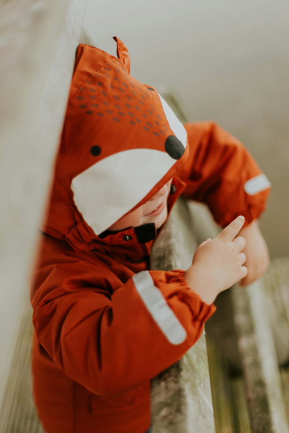 Fotografía de enfoque selectivo de niño pequeño con chaqueta de zorro naranja