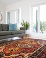 teal 2-seat couch and red area rug