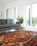 teal 2-seat couch and red area rug