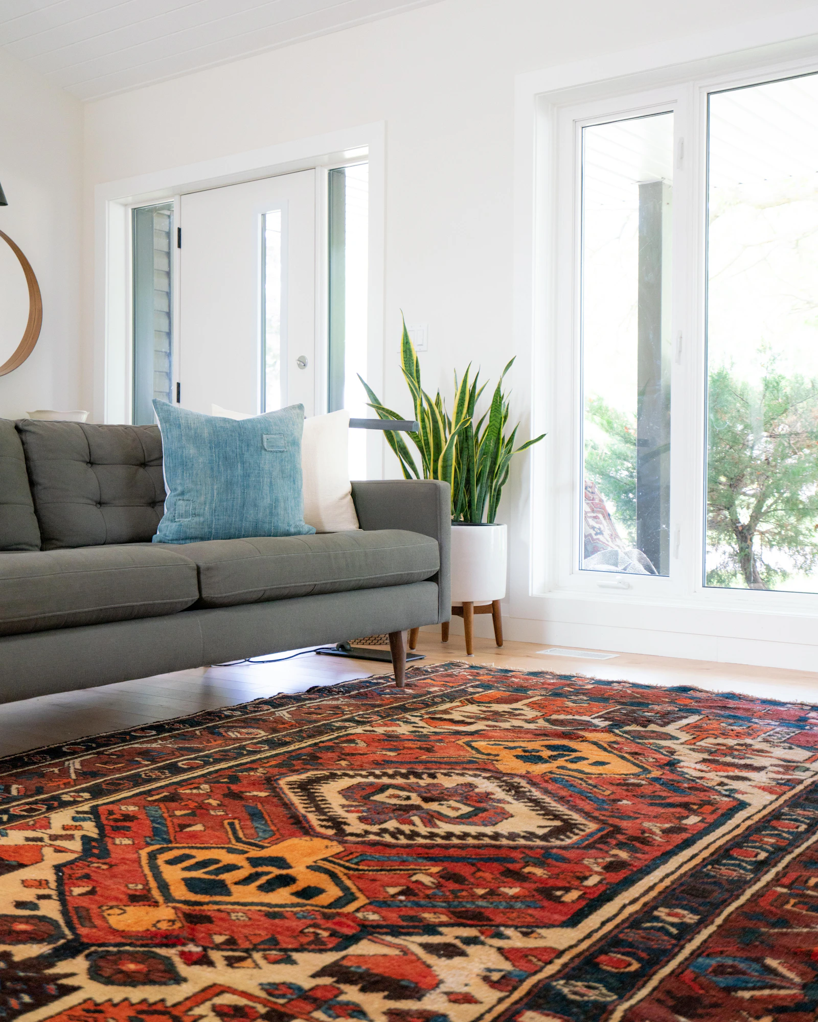 Salon lumineux avec canapé, coussins et grand tapis à motifs aux tons chauds