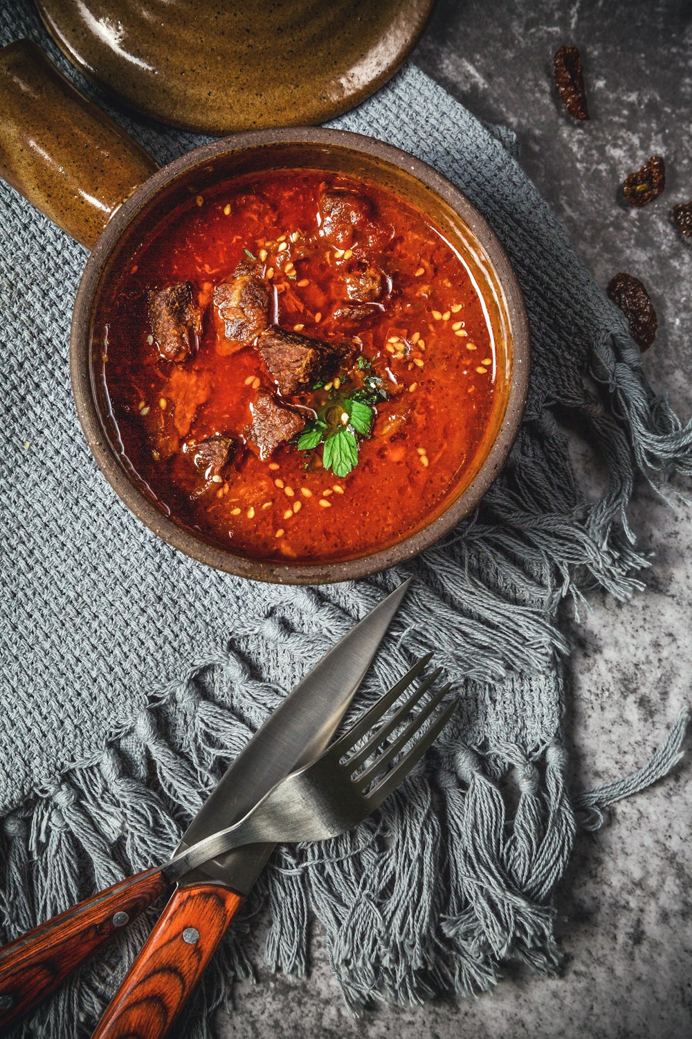 skewed meat in bowl beside knife and fork