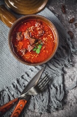 skewed meat in bowl beside knife and fork