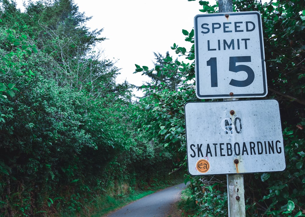 two white speed limit and no skateboarding signages near stree