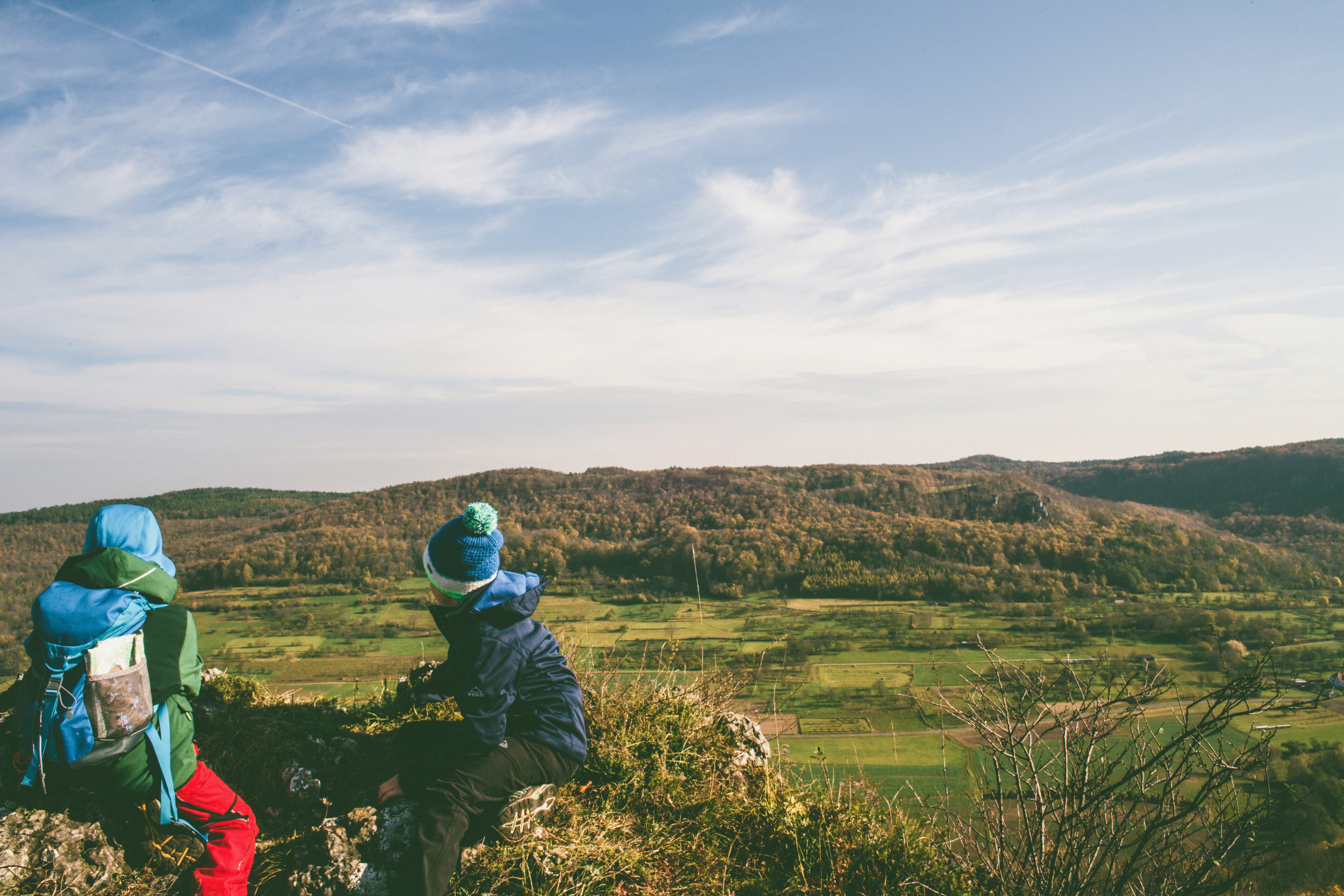 two person sitting on rock near mountain