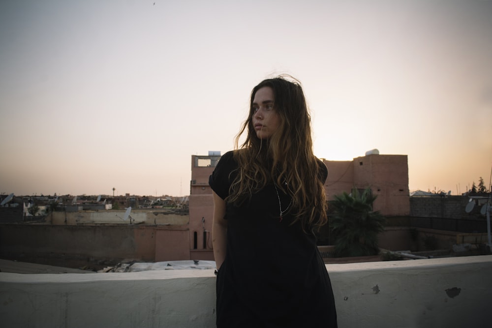 woman standing near white concrete wall during daytime