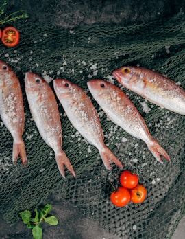 five fish between tomatoes on black net