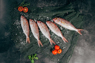 five fish between tomatoes on black net