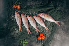 five fish between tomatoes on black net