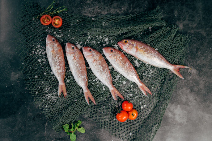 five fish between tomatoes on black net