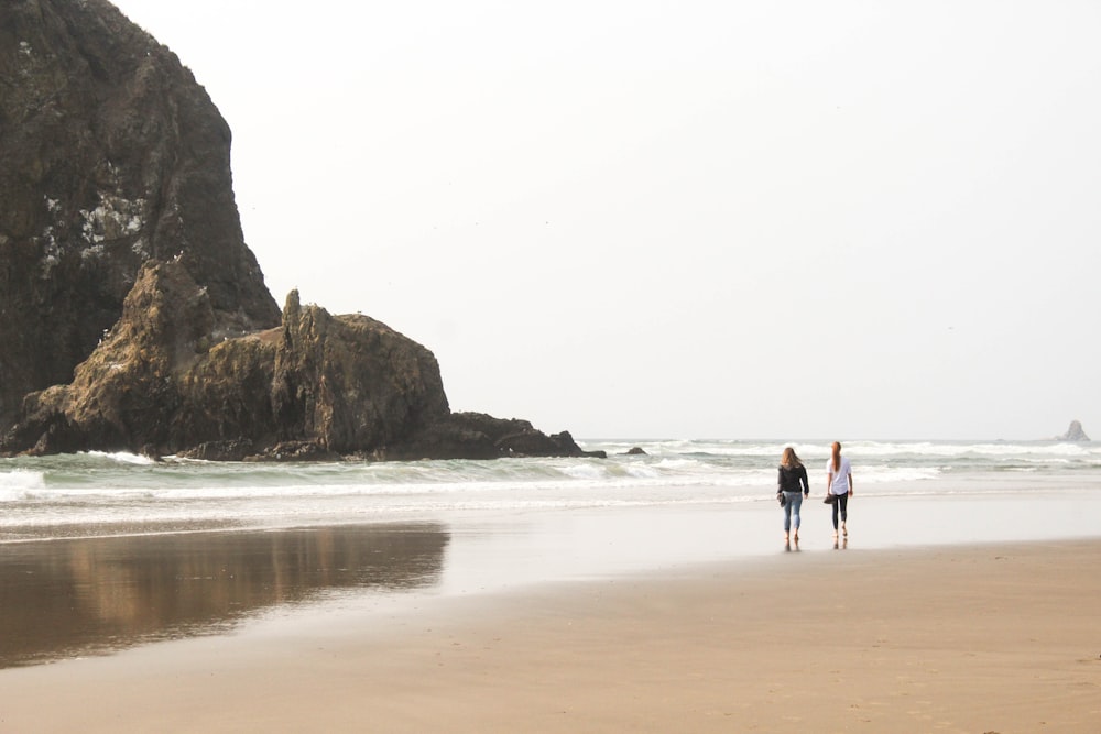 two person standing on sea shore