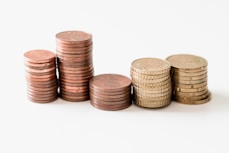 stacked round gold-colored coins on white surface