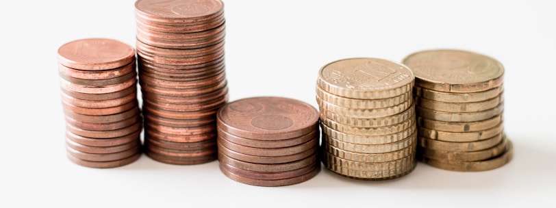 stacked round gold-colored coins on white surface