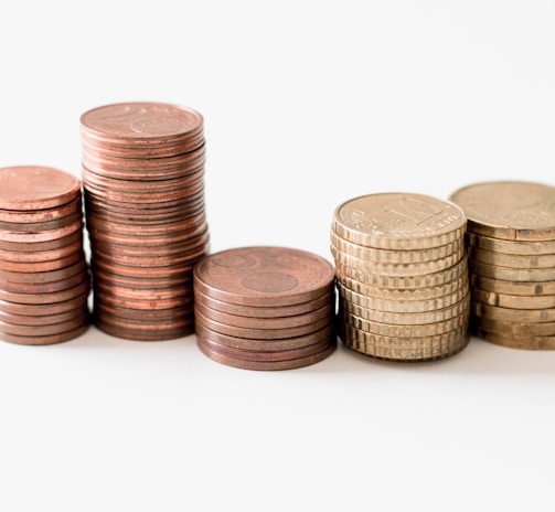 stacked round gold-colored coins on white surface