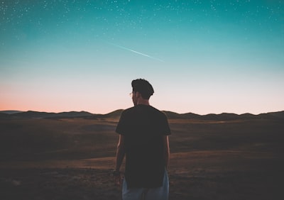 man wearing black top standing in front of mountain trips google meet background