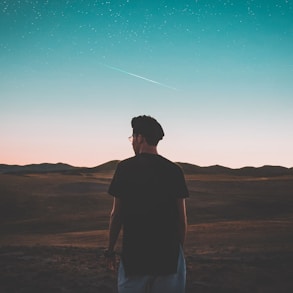 man wearing black top standing in front of mountain