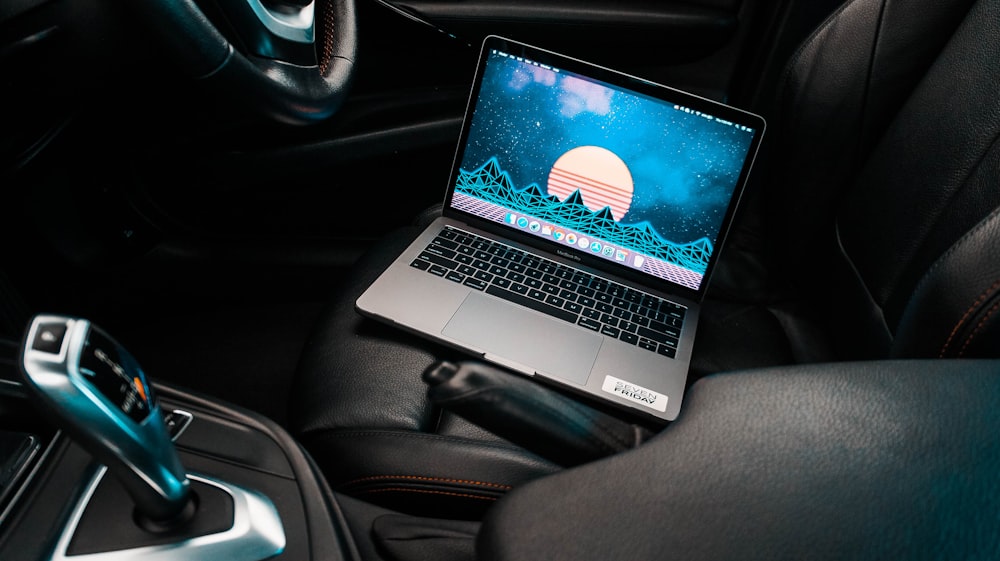 eingeschalteter grauer Laptop-Computer auf Auto-Schalensitz