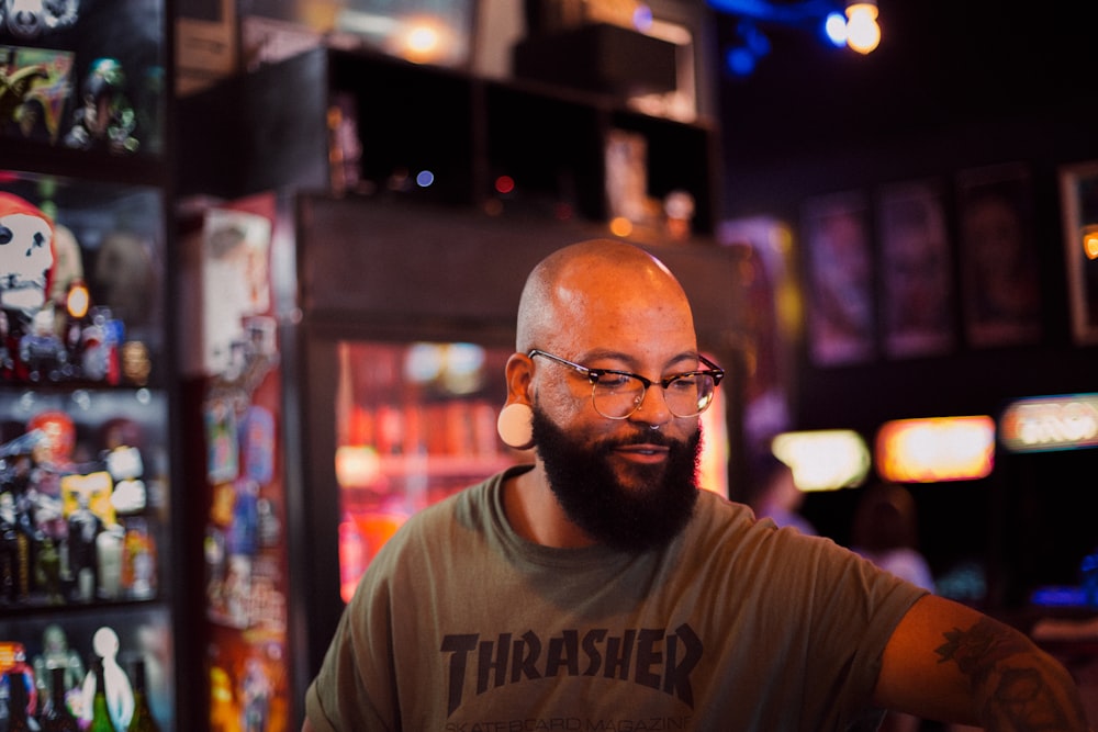 man in gray Thrasher crew-neck shirt standing near commercial refrigerator