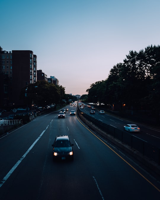 cars passing on road in between tree under blue sky in Boston United States