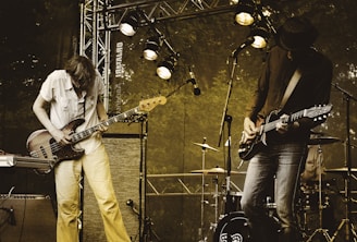 two men performing guitar on stage