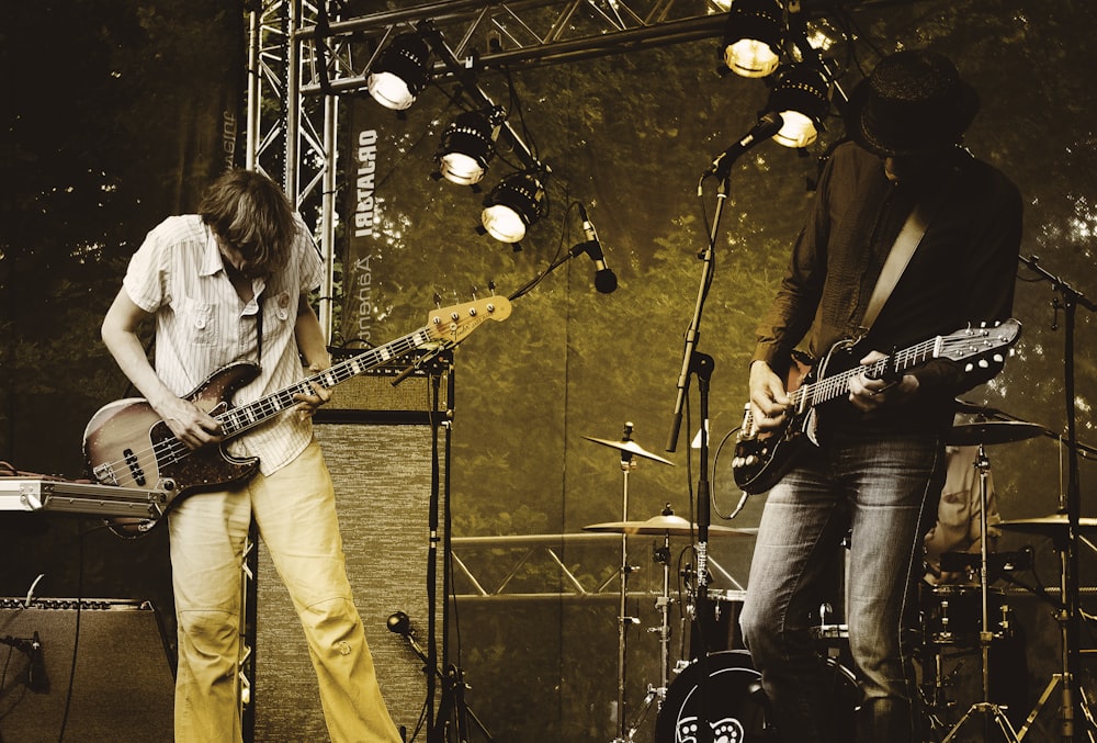 two men performing guitar on stage