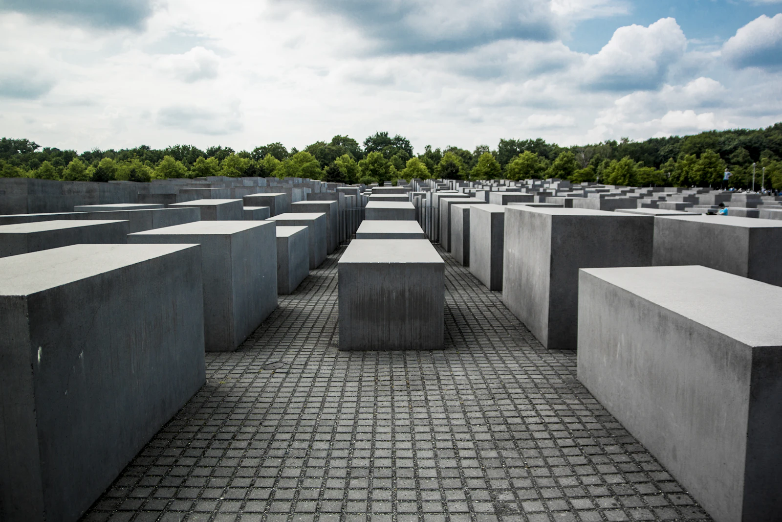Travel photograph: Rows of grey concrete stelae at the Memorial to the Murdered Jews of Europe beneath a heavy, broken sky.
