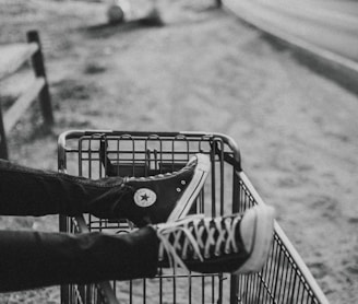 grayscale photo of person foot on metal grocery cart