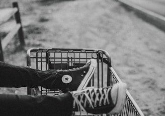 grayscale photo of person foot on metal grocery cart