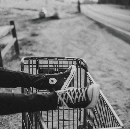 grayscale photo of person foot on metal grocery cart