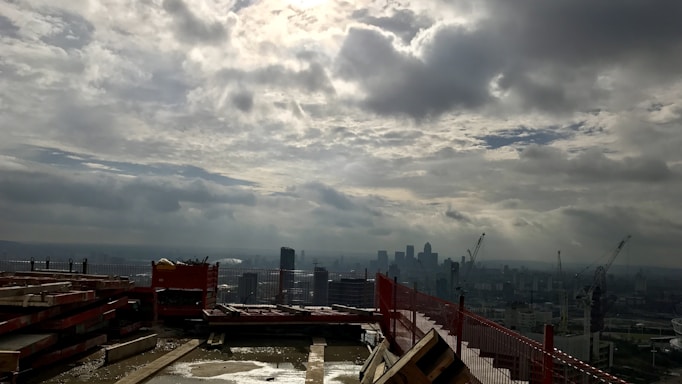 A close-up of a construction site with cement and steel beams under a cloudy sky.