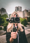 selective focus photography of woman holding camera gimbal