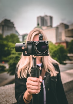 selective focus photography of woman holding camera gimbal