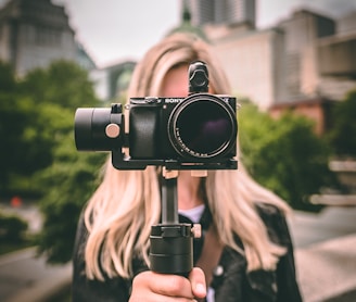 selective focus photography of woman holding camera gimbal