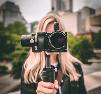 selective focus photography of woman holding camera gimbal