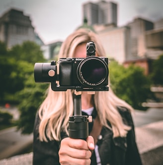 selective focus photography of woman holding camera gimbal