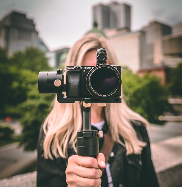selective focus photography of woman holding camera gimbal