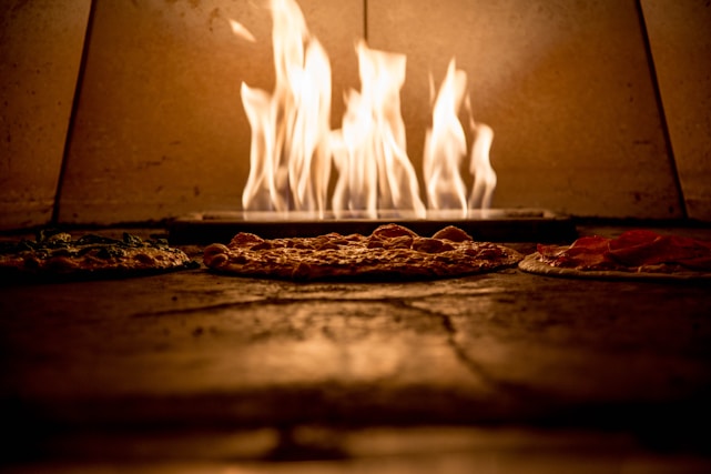 A warm, inviting pizza oven with a fresh Margherita pizza being pulled out.
