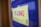 A blurred image focuses on the word 'SPELLING' written in colorful letters on a yellow background, mounted on a blue board.
