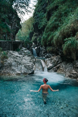 woman on body of water near waterfall during daytime