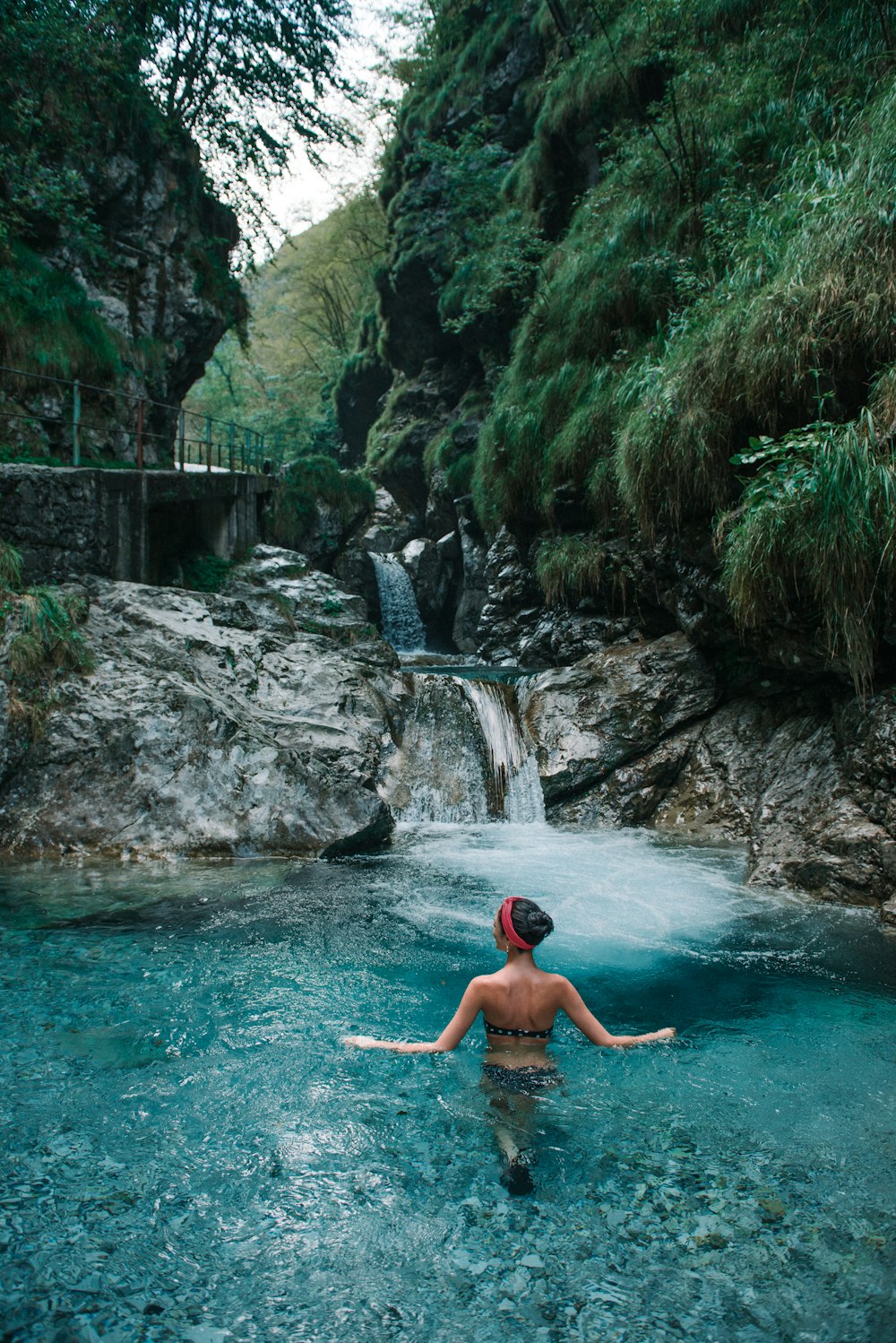 Frau tagsüber auf einem Gewässer in der Nähe eines Wasserfalls