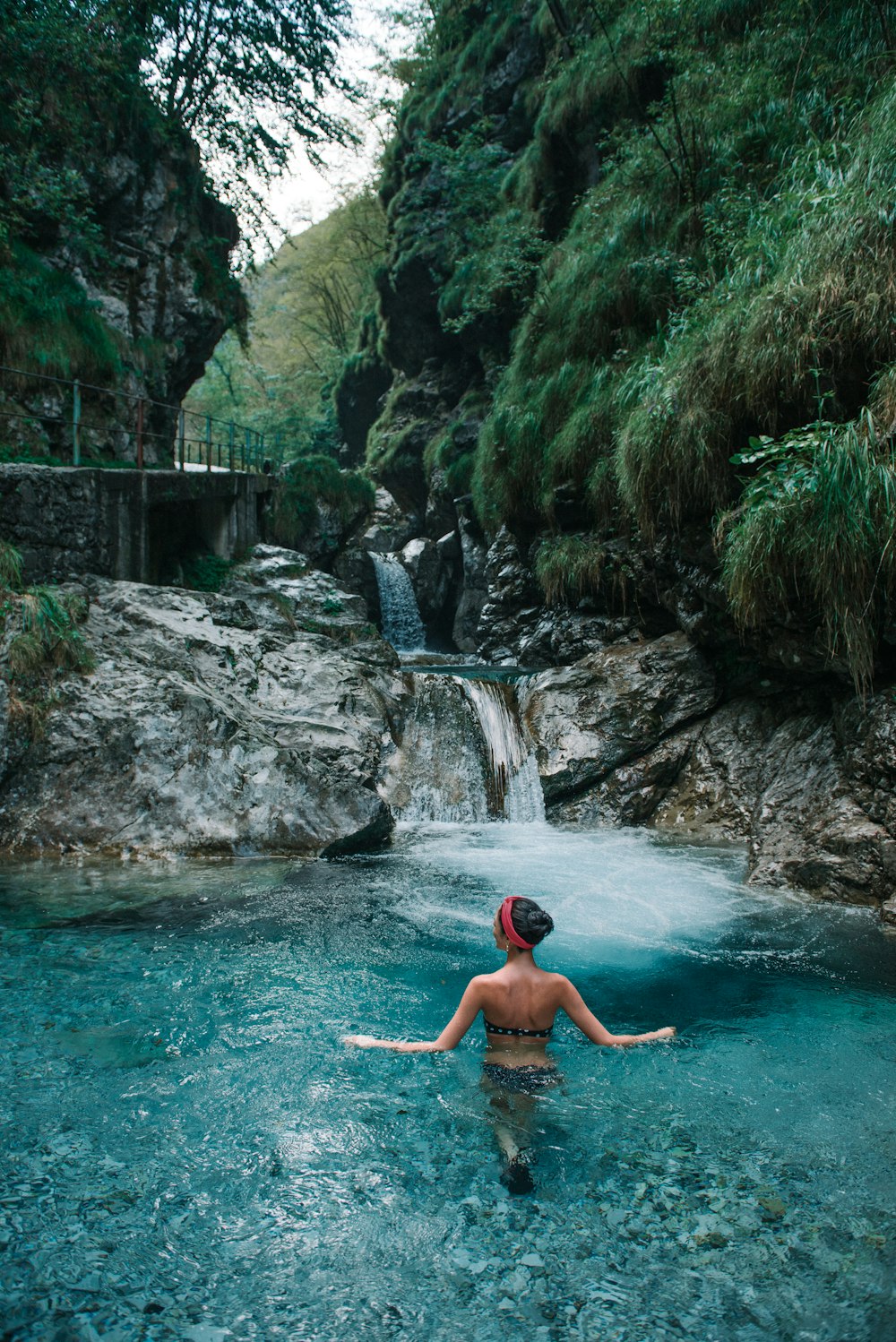 woman on body of water near waterfall during daytime