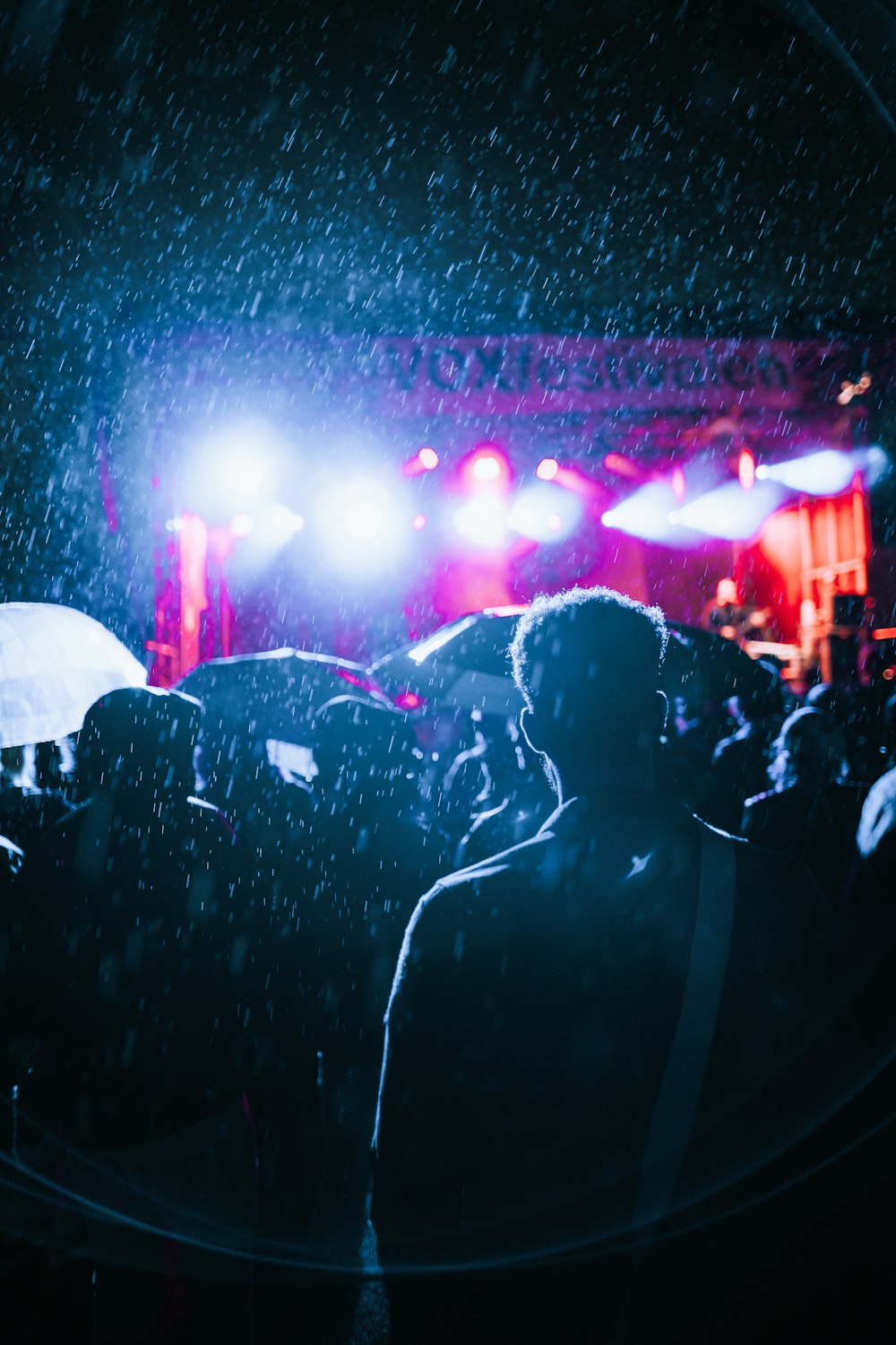 Gente viendo concierto en vivo durante la lluvia