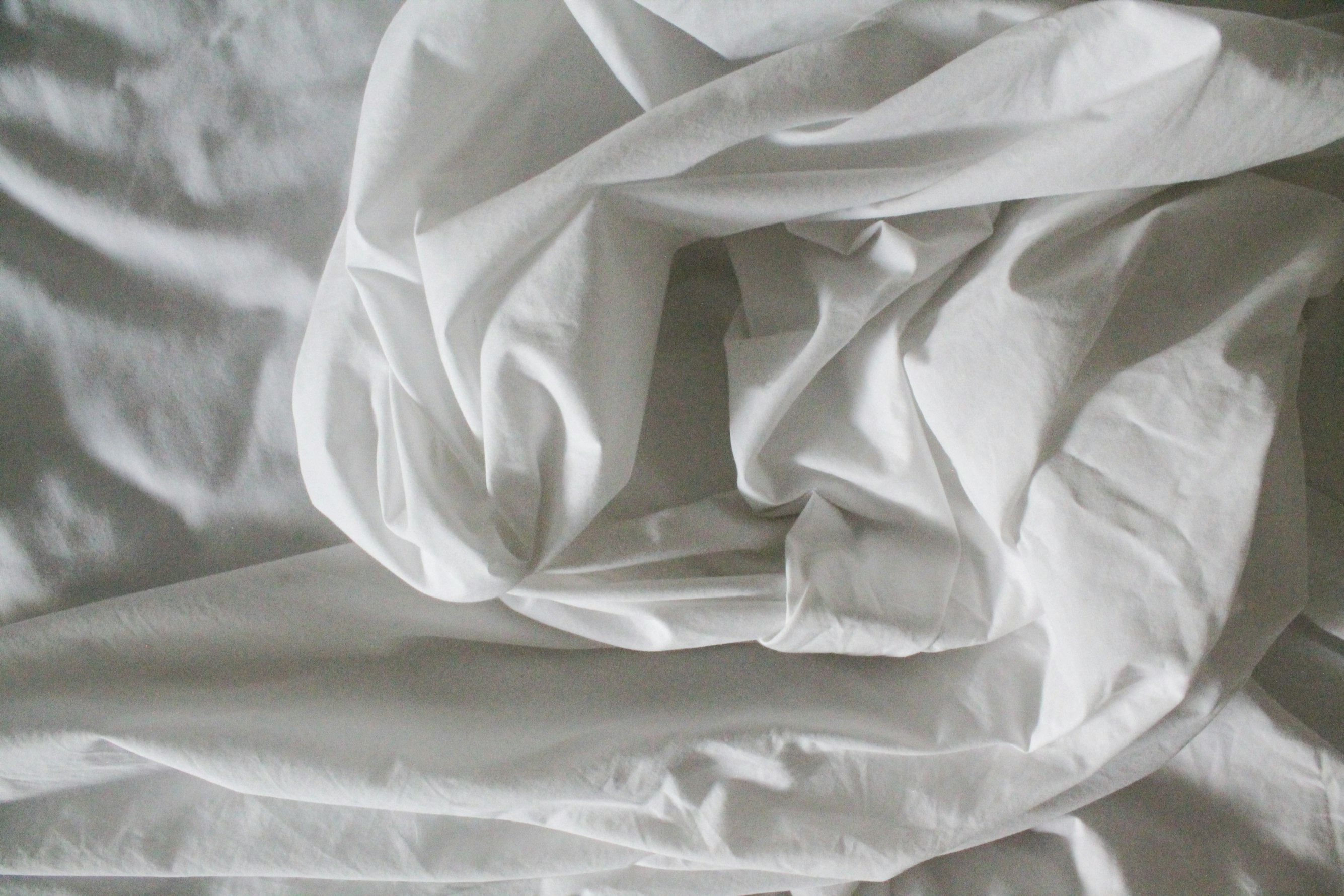 White sheets on bed - Photo by Justine Camacho on Unsplash
