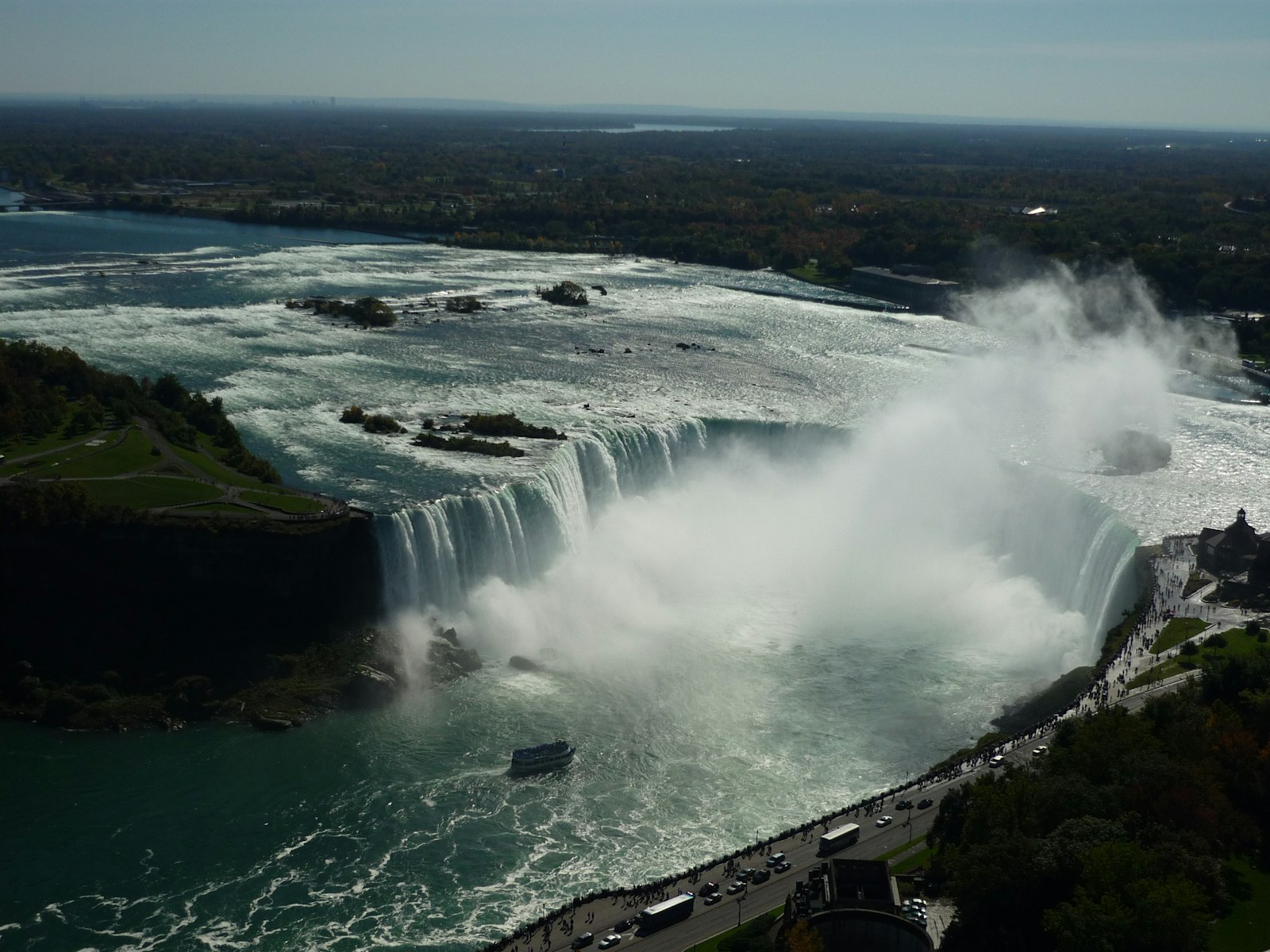 Aerial view of the Horseshoe Falls and its rising mist from the Canadian side, with the riverside promenade below