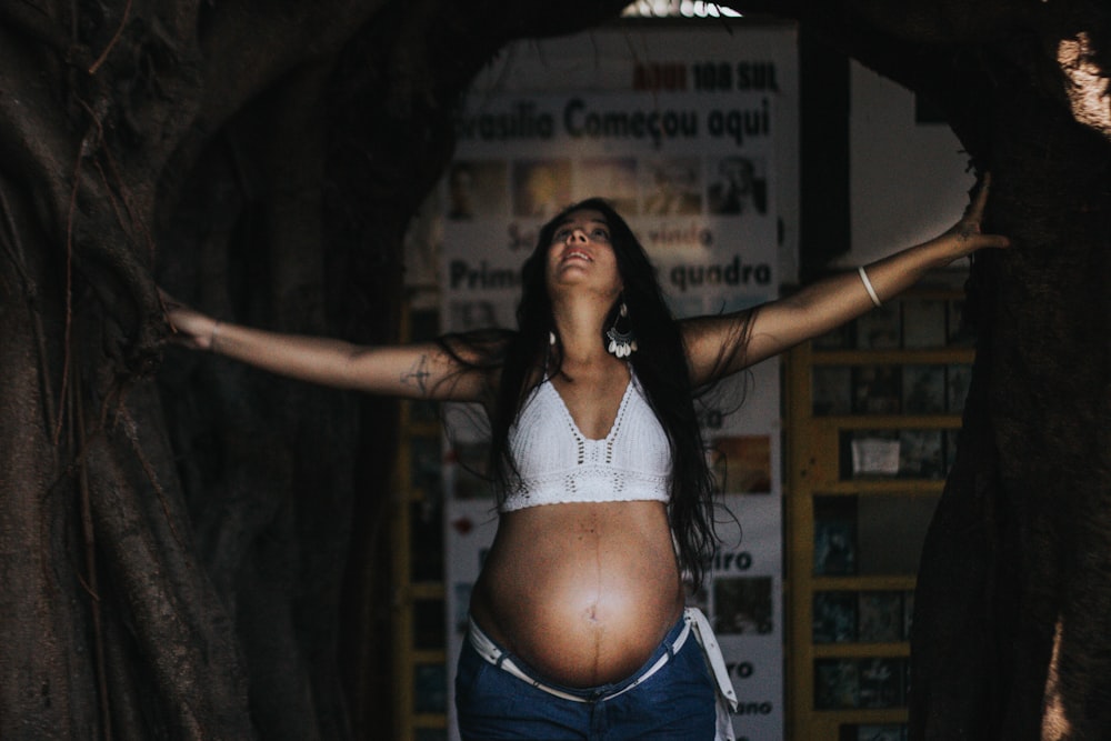 a pregnant woman standing in a tree tunnel