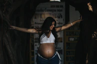 a pregnant woman standing in a tunnel with her arms outstretched