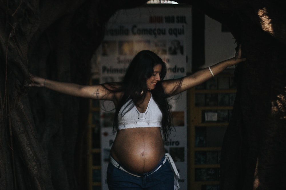a pregnant woman standing in a tunnel with her arms outstretched
