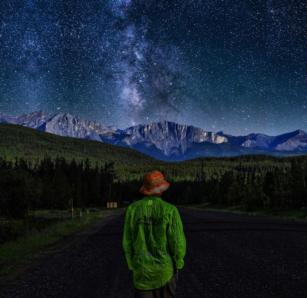 person wearing green sweater standing near the house during nighttime illustration