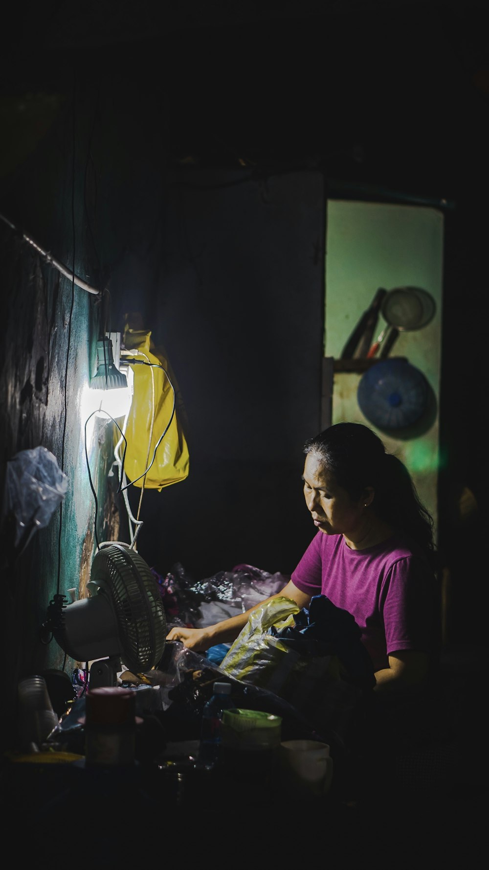 woman facing white desk fan under white lamp