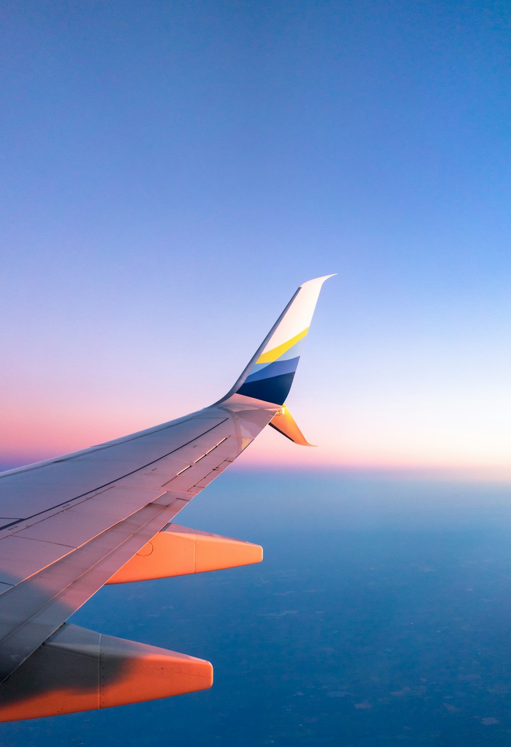 푸른 하늘 아래 흰색과 주황색 비행기의 사진을 찍는 사람